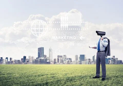 Camera headed man standing on green grass against modern citysca Stock Photos