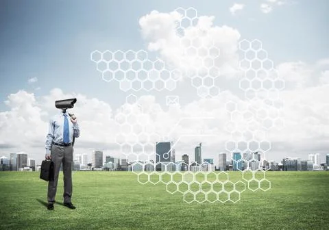 Camera headed man standing on green grass against modern citysca Stock Photos