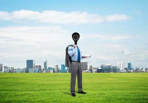 Camera headed man standing on green grass against modern cityscape Stock Photos