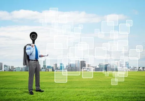 Camera headed man standing on green grass against modern cityscape Stock Photos