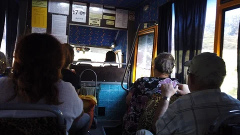 Camera inside the bus. The bus stops. An old woman comes in - sits down. Video stock 115935384
