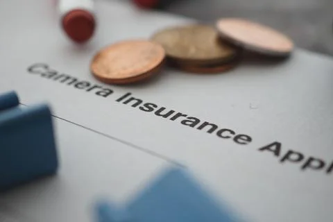 Camera insurance application form with coins on a table Stock Photos