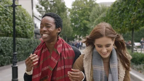 Camera leads in front of two diverse female friends walking and talking in the c Stock Footage 80328519