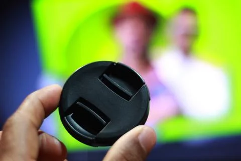 Camera lens cap with hand and colorful background Stock Photos