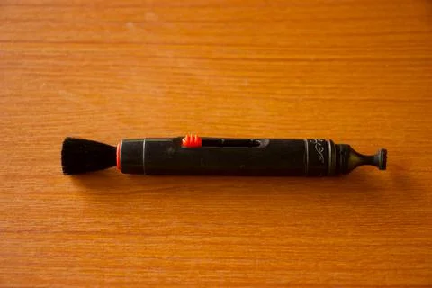 Camera lens cleaning pen placed on brown table Stock Photos