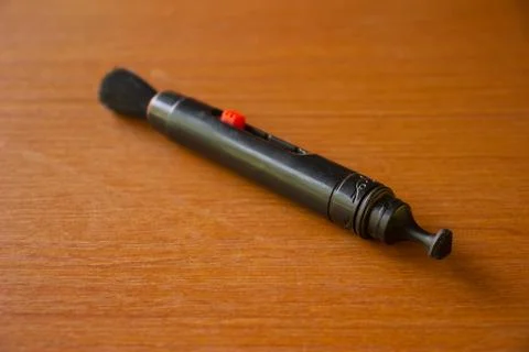 Camera lens cleaning pen placed on brown table Stock Photos