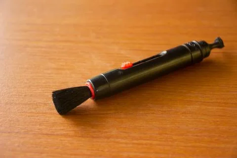 Camera lens cleaning pen placed on brown table Stock Photos