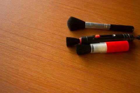 Camera lens cleaning pen placed on brown table Stock Photos