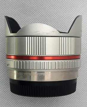 Camera lens featuring textured focus rings, red accent band, and protective hood Stock Photos
