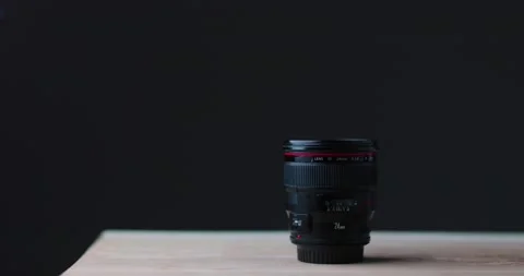 Camera lens on modern wood table with simple black background studio lights Stock Footage 237547103