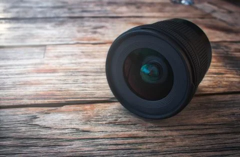 Camera lens on a rustic wooden table with soft light Stock Photos