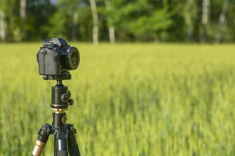 A camera with a lens on a tripod, ready for taking photos or videos in nature Stock Photos