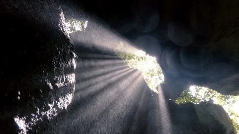 Camera look from above on the light beams goes through the rocks to the cave Stock Footage 98516983