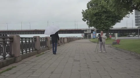 Camera man films senior model walking on river embankment Stock Footage 146324533
