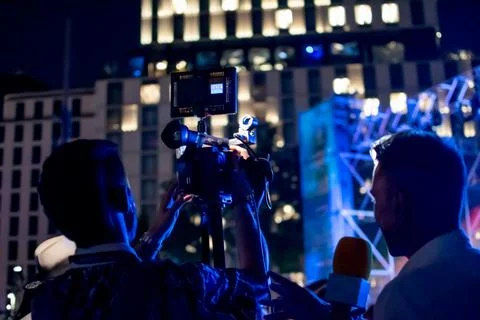 Camera man recording while organizing scene with interviewer at night event Stock Photos
