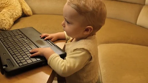 Camera motion around cute baby looking into notebook screen Stock Footage 83925838