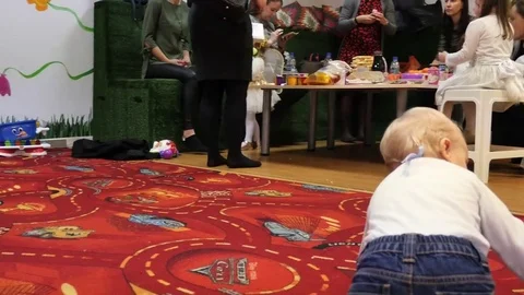 Camera motion around cute playing baby boy with people background Stock Footage 83755785