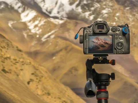 Camera mounted on tripod capturing serene mountain landscape Stock Photos