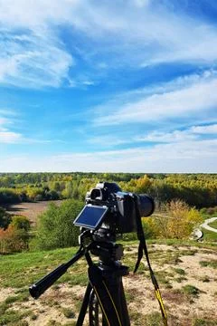 Camera mounted on tripod overlooking forested valley viewpoint Stock Photos