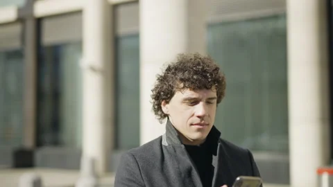 Camera Move Around: A young man stands, takes out his phone, takes pictures. Vidéo 200140442