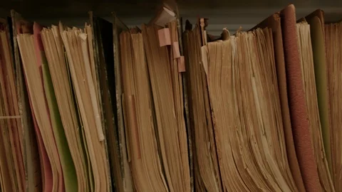 Camera movement along a file shelf. The files are old, the paper is yellowed. Видео 95427779