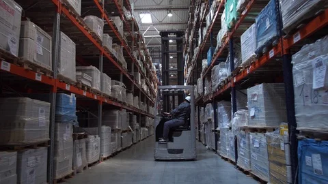 Camera movement between the racks with the goods. Ahead is a man on a forklift Stock-Footage 111766343
