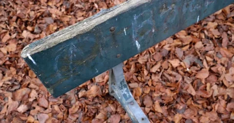 Camera movement on broken bench at the park with the floor full of dry leaves Stock Footage 146994901