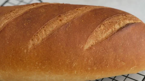 Camera movement. Close-up of hot wheat bread lies on a lattice on a light table Stock Footage 146141820