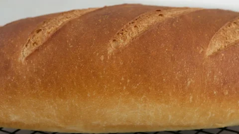 Camera movement. Close-up of hot wheat bread lies on a lattice on a light table Stock Footage 152479654