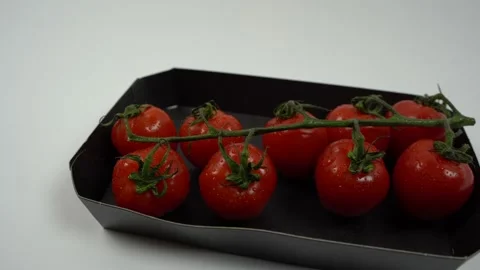 Camera movement from left to right on red wet tomatoes in black paper packaging Stock Footage 167774891