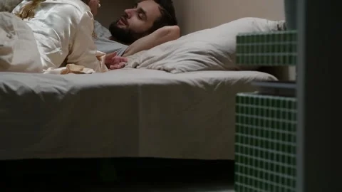 Camera movement revealing a young married couple lying in bed Vídeos de archivo 329939839