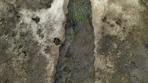 Camera moves from above and shoots the flow of a dirty melted puddle in spring Stock Footage 237162154