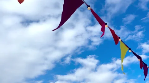 Camera moves across an array of coloured flags swaying in the breeze against the Video stock 335385002