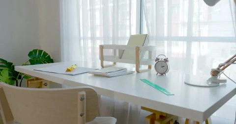 Camera moves across modern child study table with open notebook, pencil, clock, Stock Footage 335763845