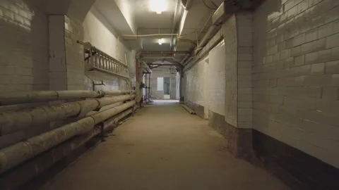 Camera moves along the basement corridor , along the walls are pipes and Vídeos de archivo 127954299