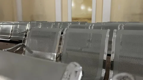 Camera moves along rows of gray metal chairs in train station waiting room Stock Footage 308923439