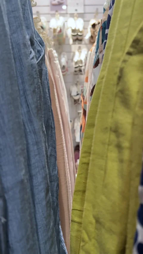 Camera moves along shelf with blue jeans pants, green cotton shirt in store Stock Footage 308562133