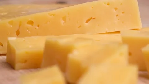 Camera moves along slice of yellow cheese with holes on cutting board Stock Footage 231516924