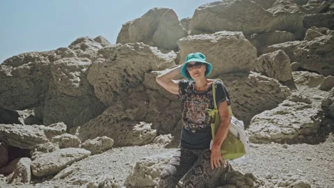 Camera moves away from pretty elderly woman standing on mountain hiking trail Stock Footage 222678735