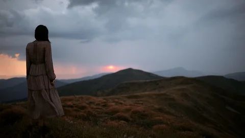 The camera moves behind a young beautiful woman in a long dress. Girl stands on Stock Footage 118588006
