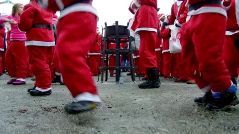 Camera moves between crowd of young kid children happy Santa Clauses dancing Stock Footage 70639303