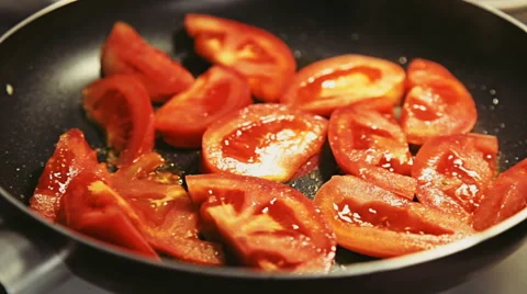 Camera moves close to the frying pan where tomato slices are roasting Stock Footage 65524379