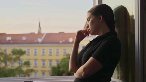 Camera moves closer to pensive young woman by a window in a dramatic moment Stock Footage 221241680