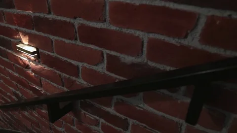 Camera moves down an empty staircase along a brick wall with lamps in the loft Video stock 111812170