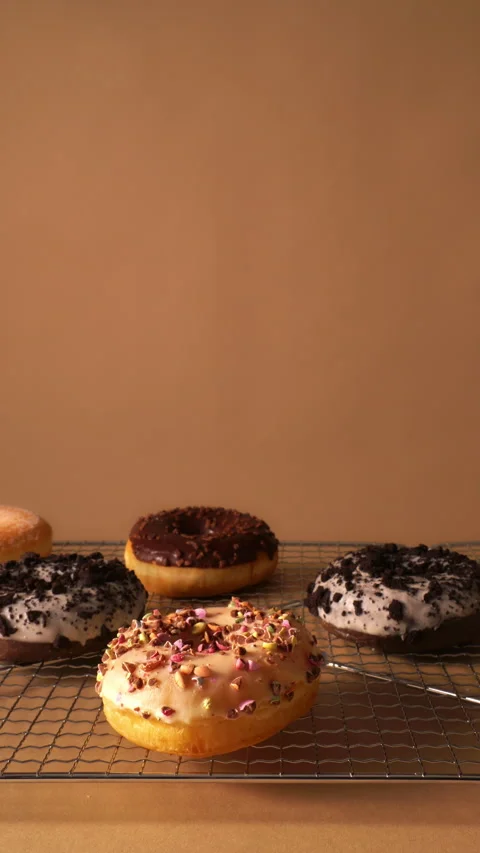 Camera moves downward over assorted donuts on metal cooling rack, revealing Stock Footage 331232505