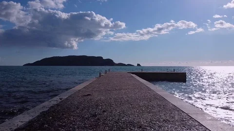 Camera moves forward from coast along stone pier into open sea , drone shooting Video stock 127721345