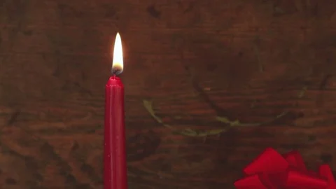 Camera moves from lit red Christmas candle to vintage present Stock Footage 80350675
