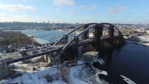 The camera moves over the bridge that is being built across the river. Aerial vi Stock Footage 72509976