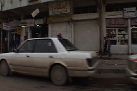 Camera moves past line of parked cars and storefronts Stock Footage 86753432