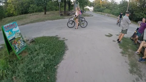 Camera moves past two beautiful smiling girls on bikes, gopro, slowmotion Stock Footage 111945518